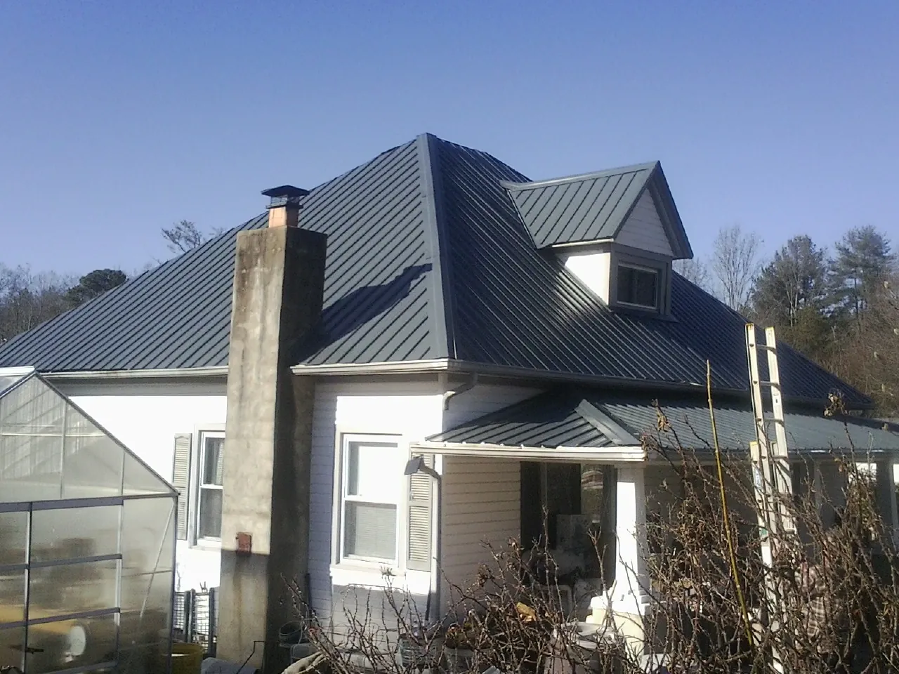 Dark blue standing seam metal roof on a white farmhouse with dormer — Slate & Tile Roof Repair by Roofing Brothers in Woodland