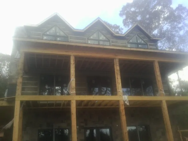 Dormers and porch framing on a large log home under construction — Roof Coating work by our crew in Woodland